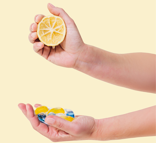 Hands holding a sliced lemon and ice cubes against a yellow background
